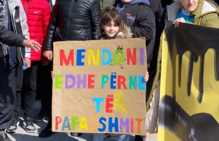 “MENDONI EDHE PËR NE…”/ Vogëlushja mban pankartën me mesazhin domethënës në protestën para Kryeministrisë