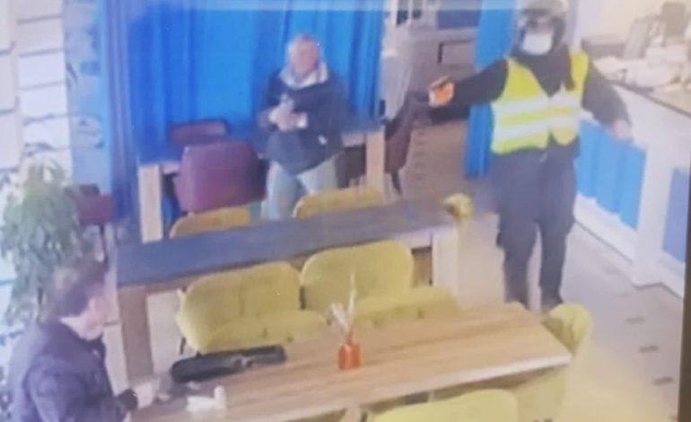 FOTOLAJM/ Biznesmeni i ulur në tavolinë, autori me skafandër e jelek i drejton armën